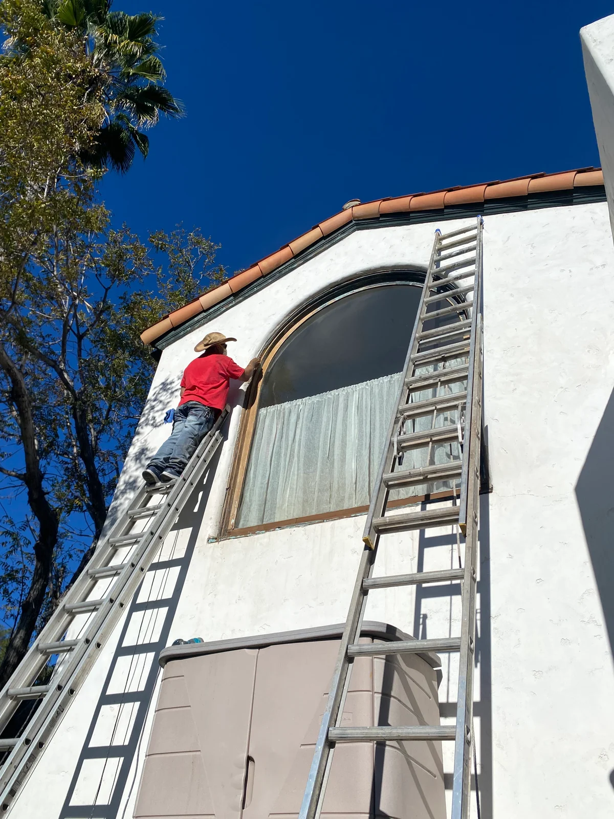 Huff Painting crew member prepping an exterior from a ladder